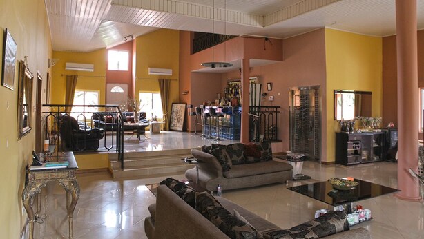 A spacious living area with a sofa set, a coffee table, and a dining area with chairs and a table. - Quest Lodge (Accra)