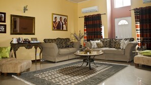 A living room with two sofas, a coffee table, a rug, a mirror, and a picture frame on the wall. - Quest Lodge (Accra)