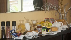 A buffet table with various food items, condiments, and a decorative tree. - Quest Lodge (Accra)