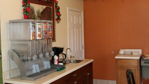 A kitchen with a coffee machine, a sink, and a cabinet. - Coach Inn (Summerville)