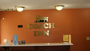 A reception desk with a sign reading "COACH INN" and a train silhouette. - Coach Inn (Summerville)