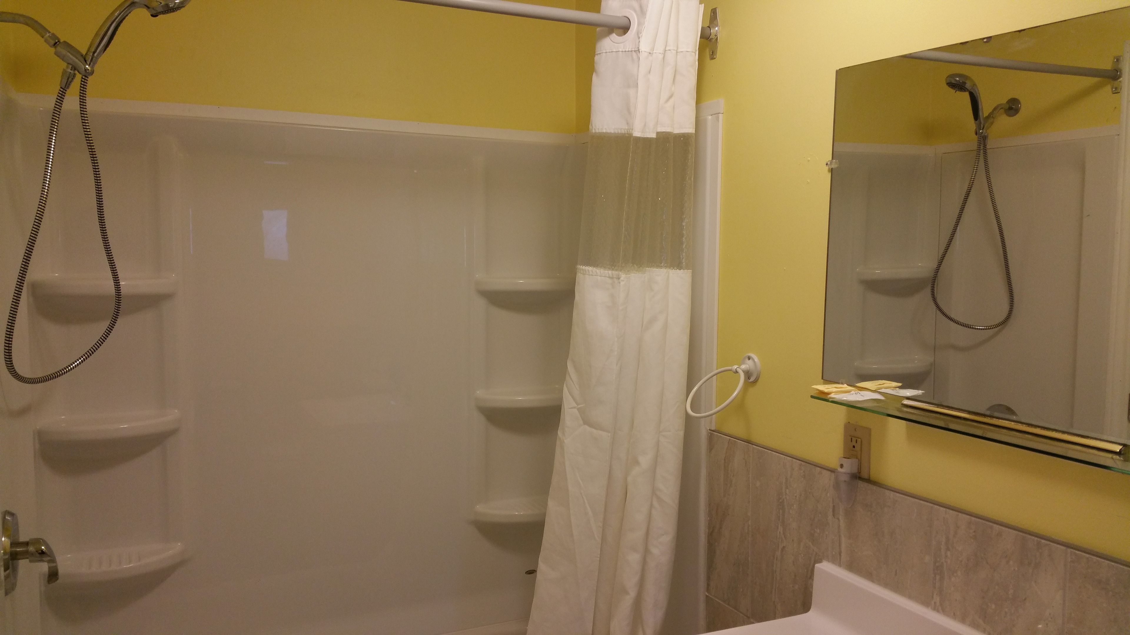 Ein Badezimmer mit Duschkabine aus Glas, einer weißen Badewanne, einem Handtuchhalter und einem Spiegel.