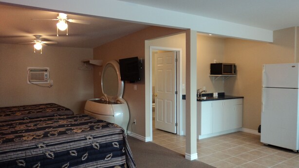 A compact hotel room with a bed, a bathroom, and a kitchenette. - Rymal's Motel (Leamington)