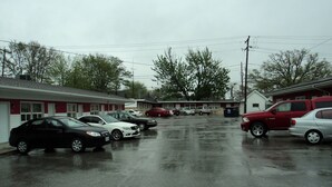A motel with a row of parked cars and a building with a red and white facade. - Rymal's Motel (Leamington)