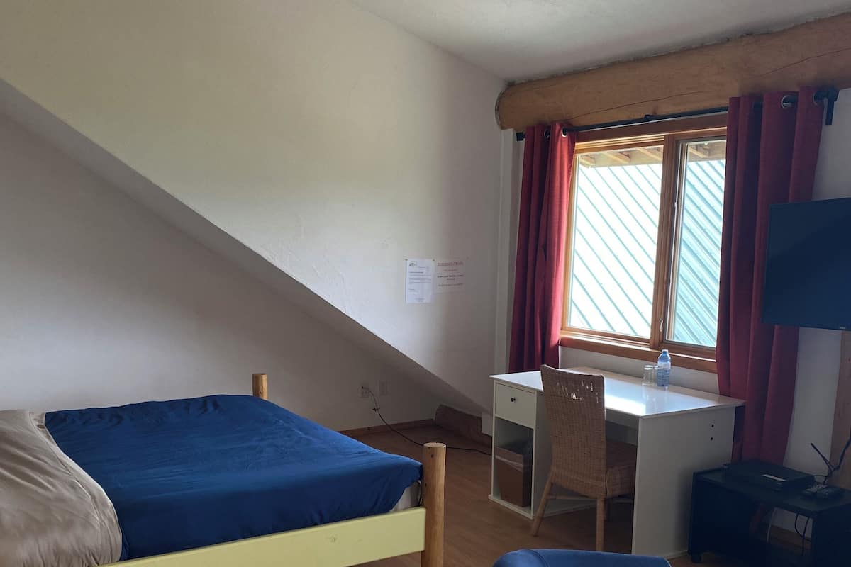 Ein Schlafzimmer mit Bett, Schreibtisch, Stuhl und Fernseher.