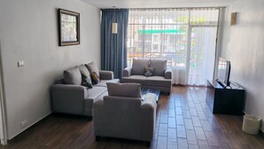Una sala de estar con dos sofás, una mesa de centro y un mueble para televisión.