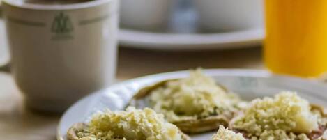 Un plato con alimentos, una taza y un vaso de zumo de naranja sobre una mesa.