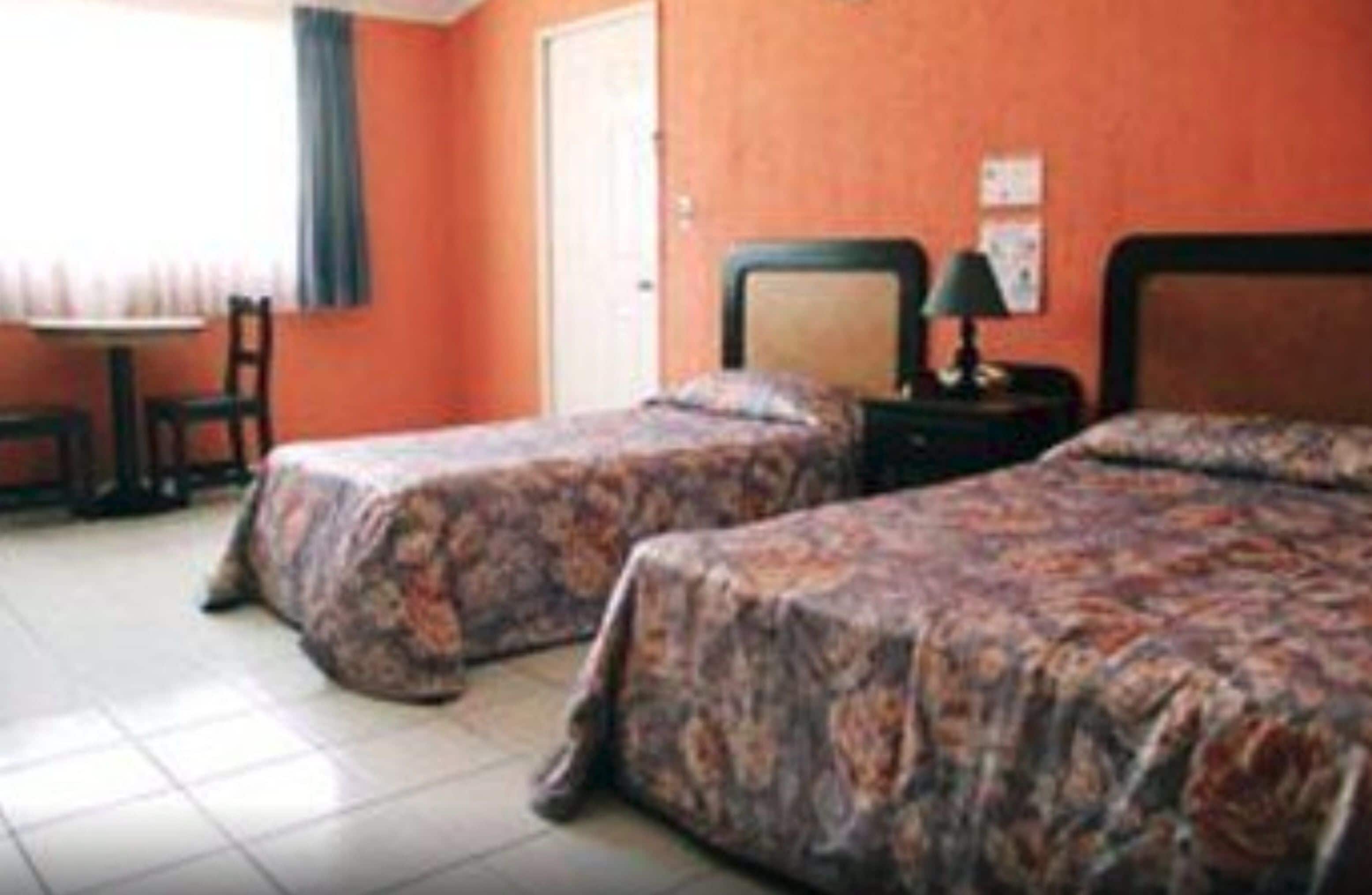Una habitación de hotel con dos camas, una mesita y una silla.