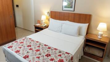 Habitación de hotel con cama, mesitas de noche, teléfono y una obra de arte colgada en la pared.