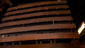Un hôtel à plusieurs étages au design moderne, doté d’une entrée imposante et d’une enseigne lumineuse.