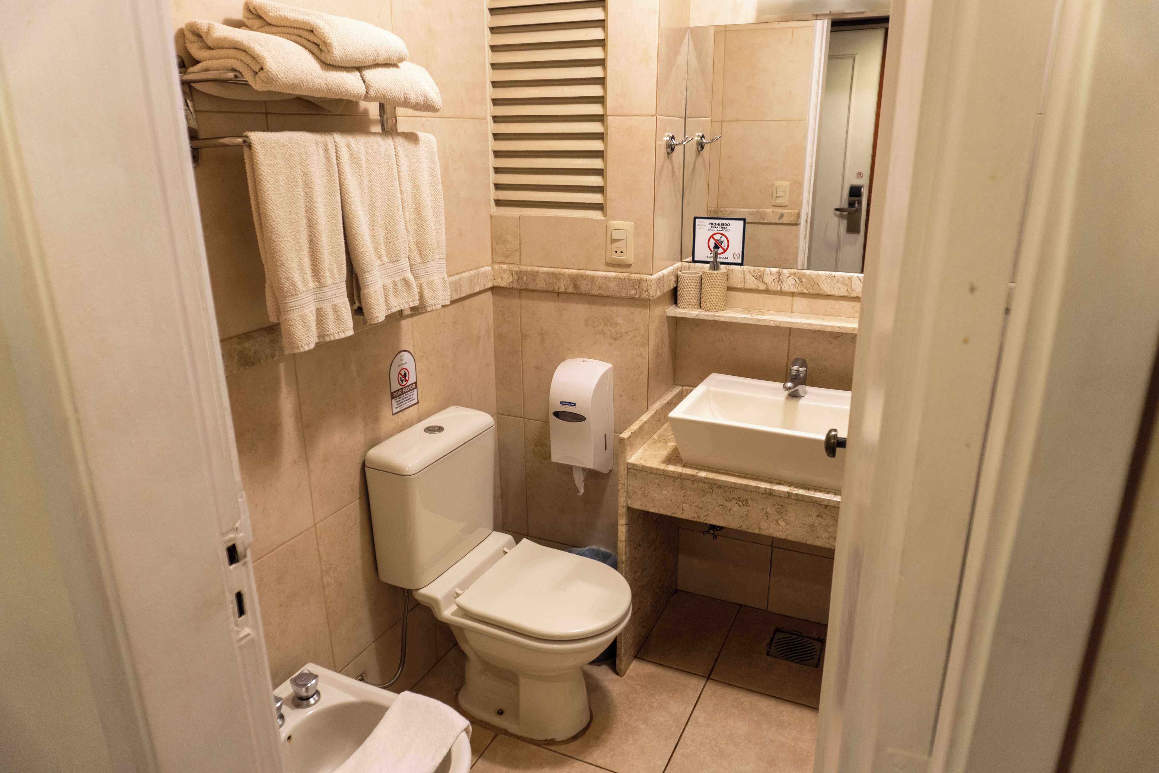 Un baño pequeño con inodoro, lavabo y toallero.