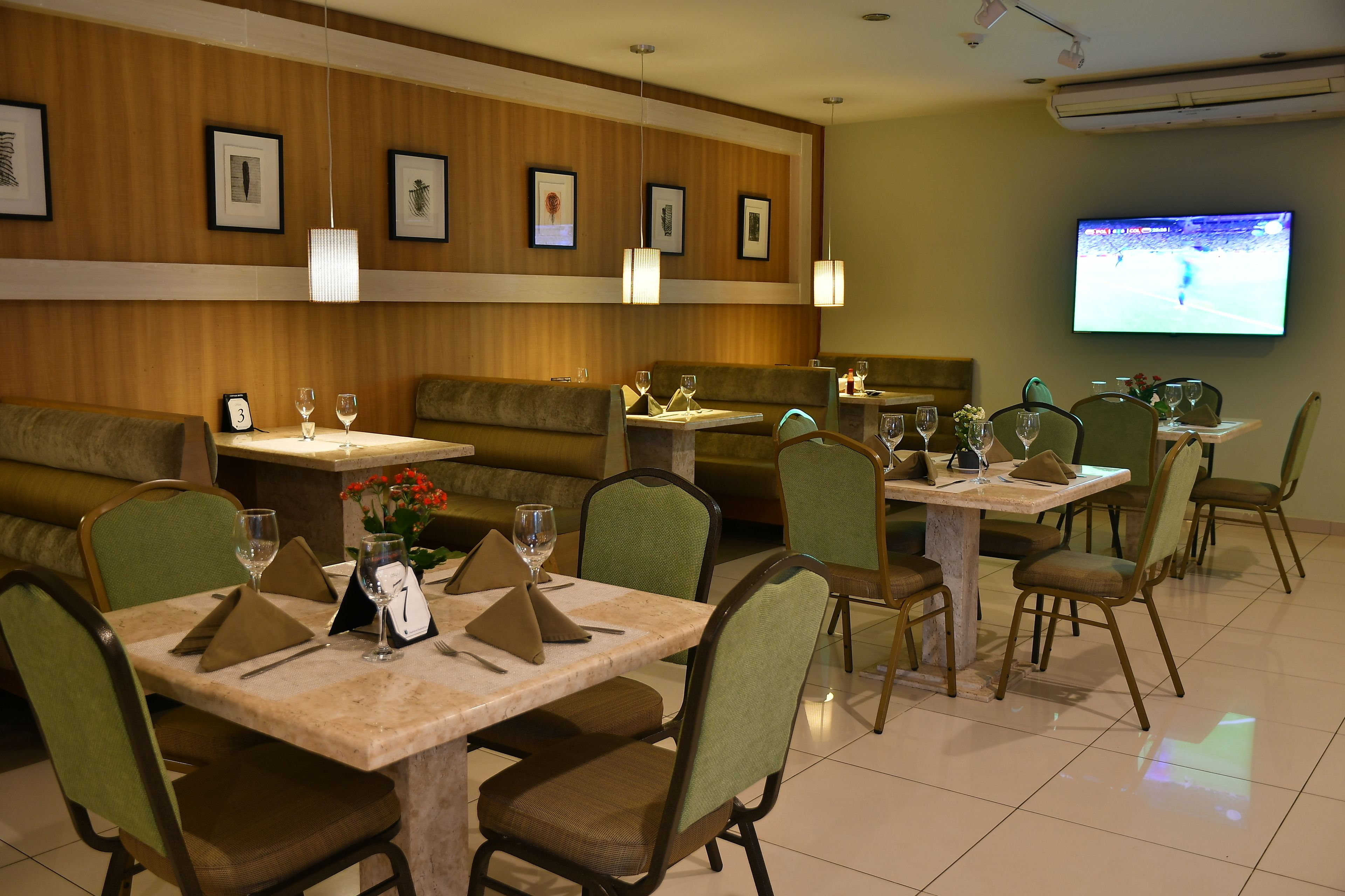 A restaurant with booths and tables, some with wine glasses and napkins.