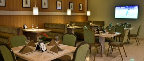 Un restaurante con cabinas y mesas, algunas con copas de vino y servilletas.