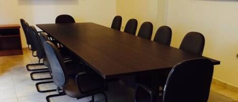 Un salón de conferencias con una larga mesa y sillas, un televisor de pantalla plana y un cuadro abstracto en la pared.