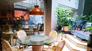 Une table de salle à manger au plateau en verre, entourée de chaises en osier, avec une lampe suspendue au-dessus.