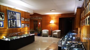 Un hall d'entrée avec une vitrine exposant des maquettes d'avions, un comptoir d'accueil en bois et des photographies encadrées accrochées au mur.