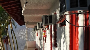 A corridor with air conditioning units, red doors, and a tiled floor. - Residencial Sol e Mar de Floripa (Florianópolis)
