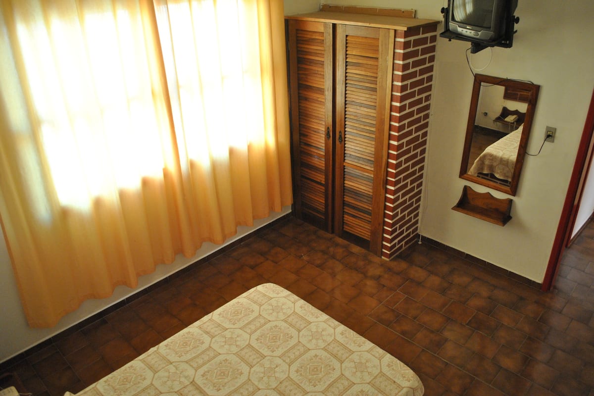 A room with a bed, a wardrobe, a television, and a mirror.