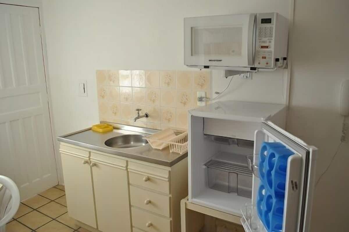 A compact kitchen with a microwave, sink, and a refrigerator with a freezer compartment.