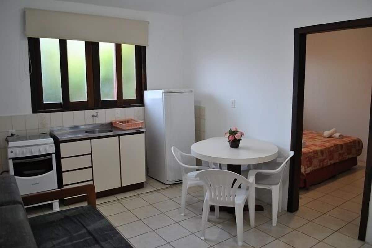 A compact kitchen with a stove, refrigerator, and a dining area with a table and chairs.