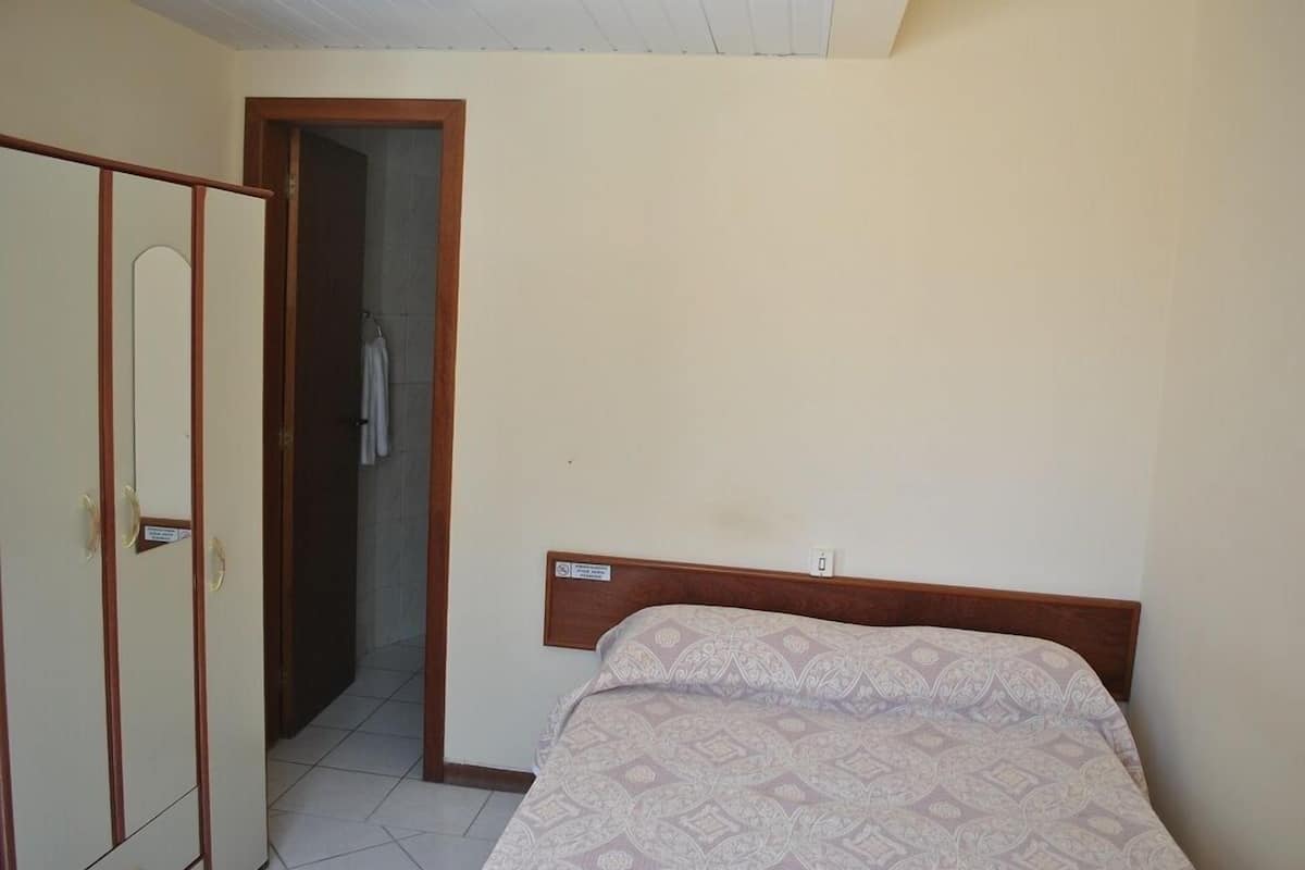 A bedroom with a bed, a wardrobe, and a door leading to a bathroom.