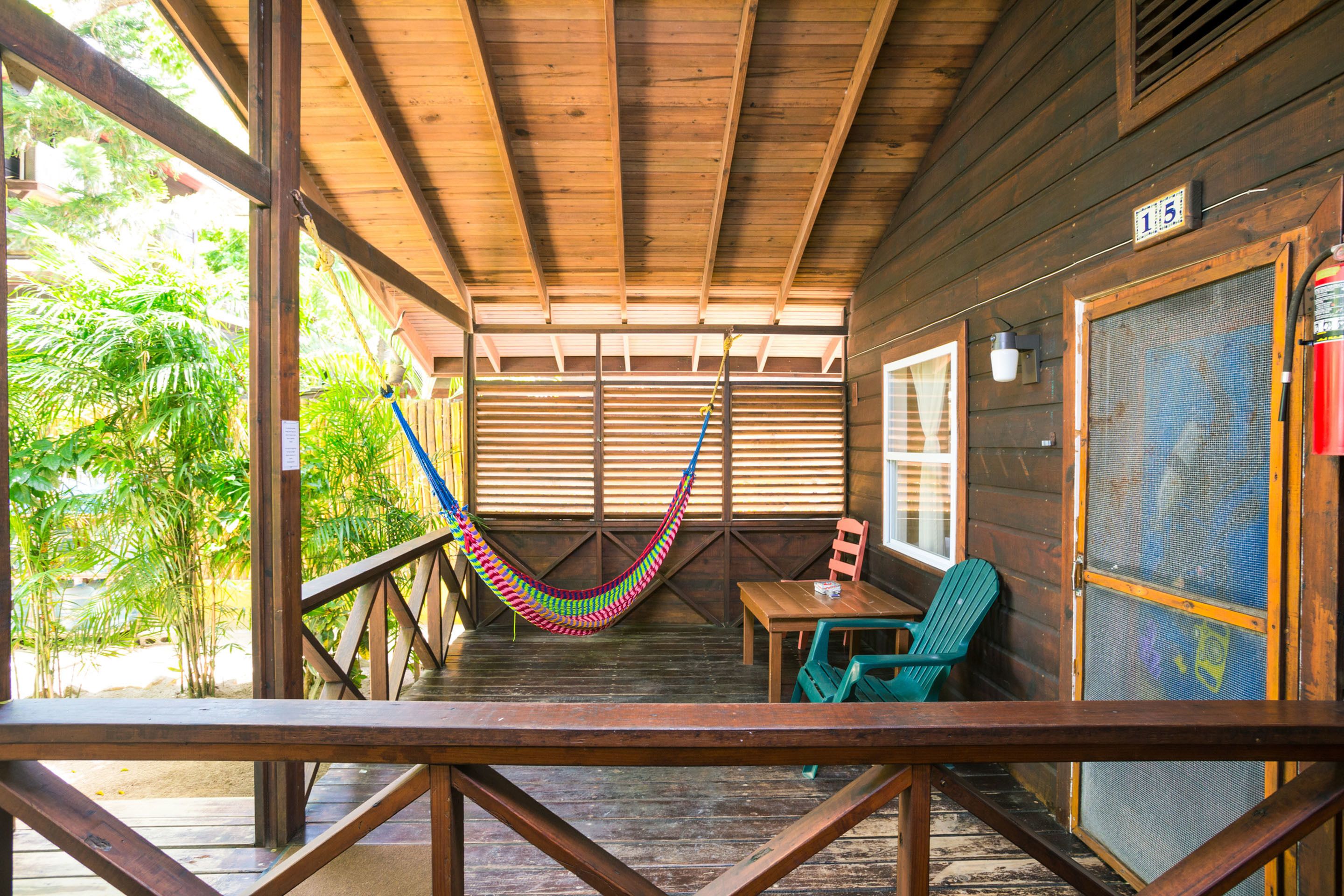 A wooden deck with a hammock, a table, and chairs.