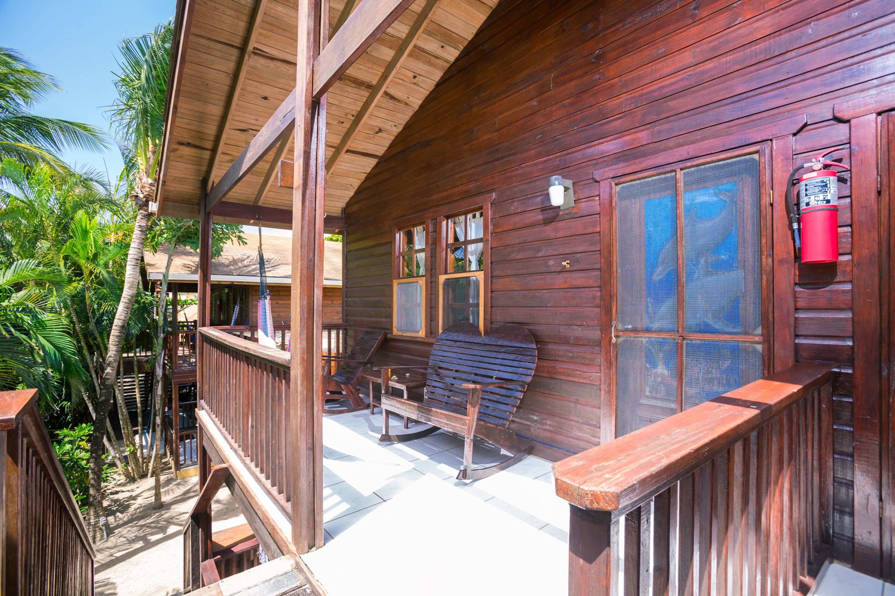 Une cabane en bois avec une véranda, des fauteuils à bascule et un extincteur.