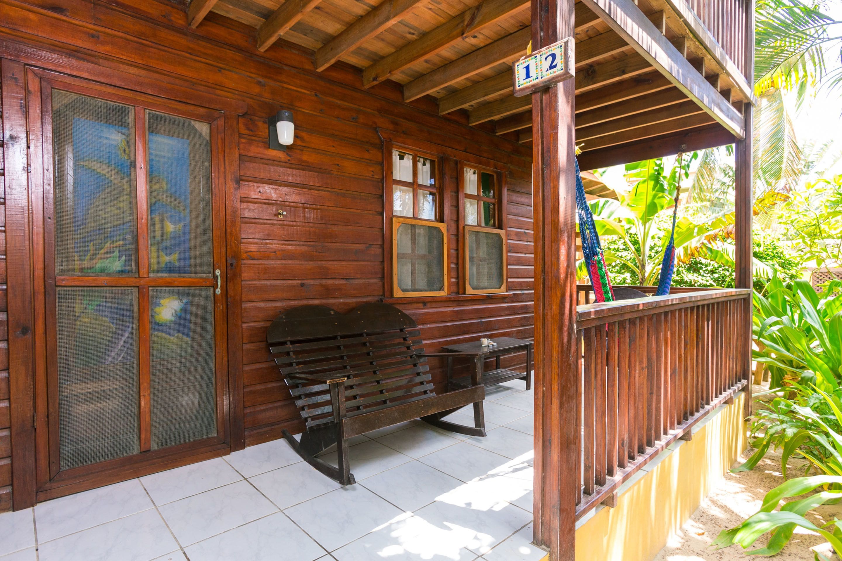 Eine Holzhütte mit einer Veranda, einer Bank und einem Schild mit der Nummer 12.
