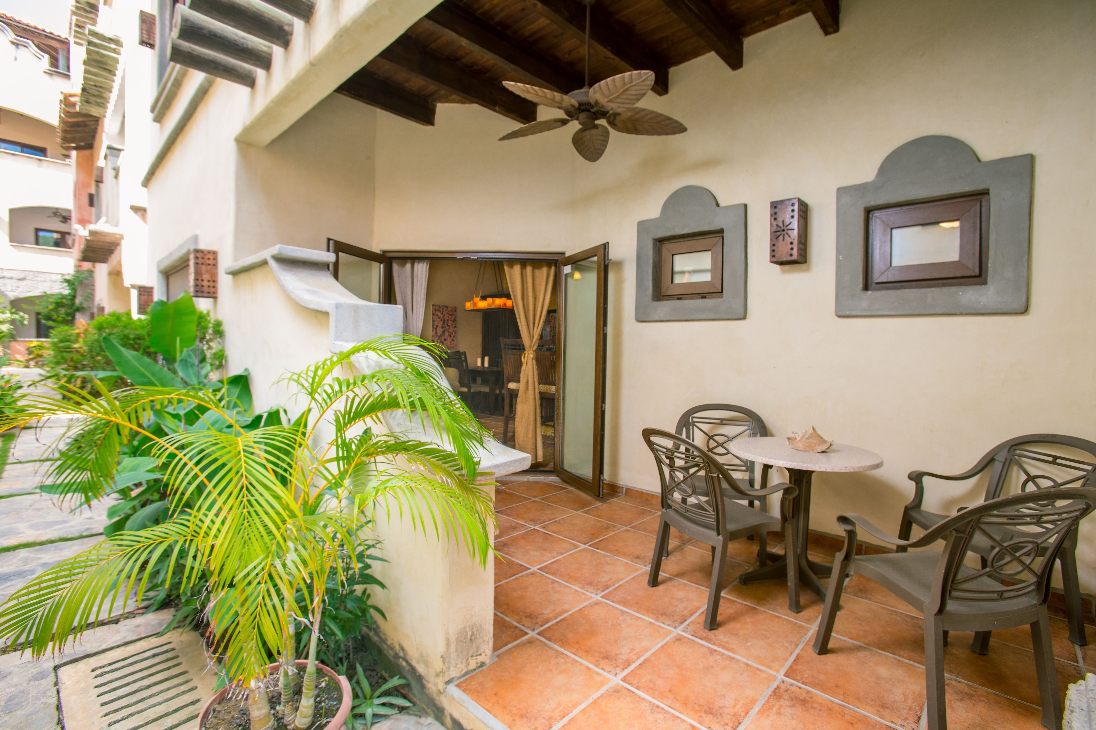 Un espacio de patio con ventilador de techo, mobiliario exterior y plantas en macetas.