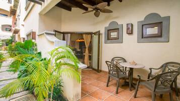 Un espacio de patio con ventilador de techo, mobiliario exterior y plantas en macetas.