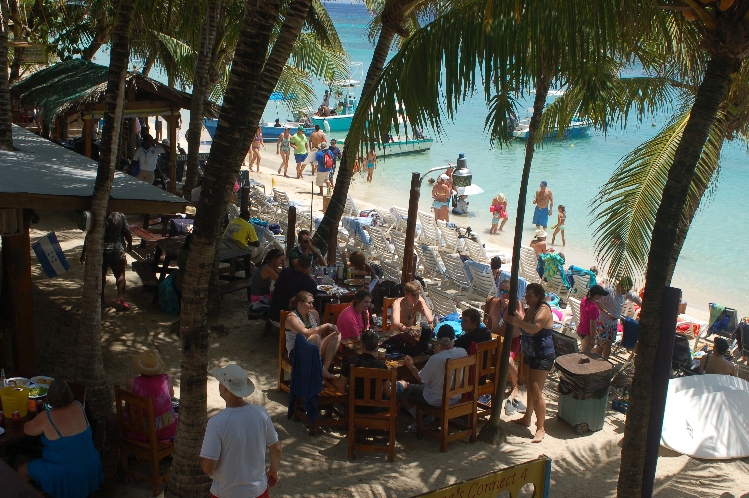Un restaurante frente a la playa con terraza, palmeras y vistas al océano.