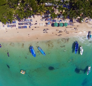 En la playa, playa de arena blanca, camastros y sombrillas