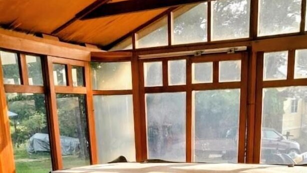A hot tub with a wooden exterior, large windows, and a view of the outdoors. - The Jay Village Inn (North Troy)
