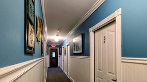 A hallway with blue walls, white trim, and a door marked with the number 5. - The Jay Village Inn (North Troy)