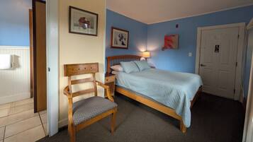 A bedroom with a wooden bed, a chair, and two framed pictures on the wall.