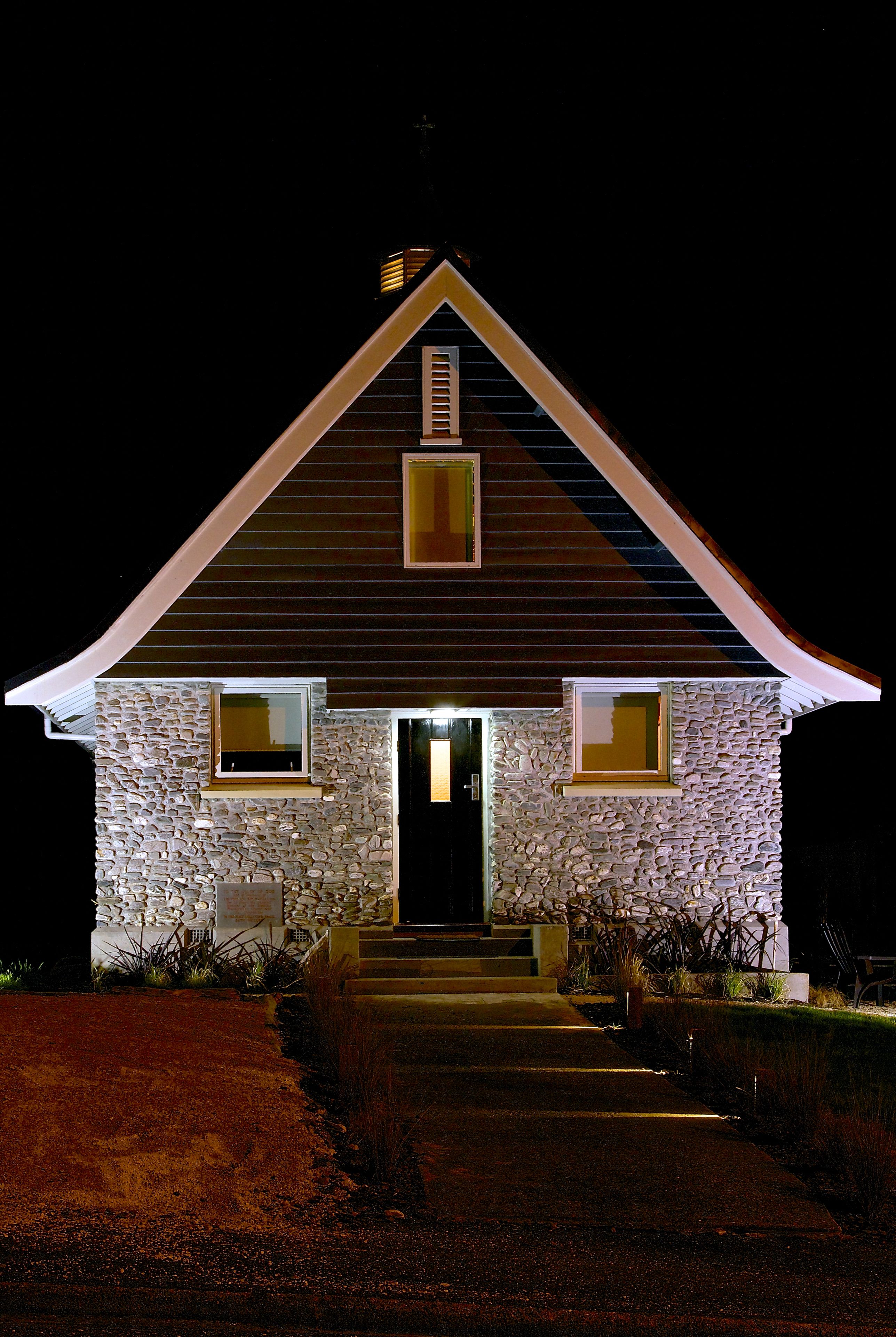 A stone building with a gabled roof and a front entrance.