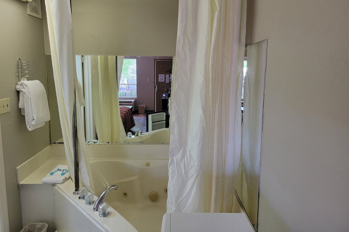 Ein Badezimmer mit Badewanne, Waschbecken, Spiegel und Duschvorhang.