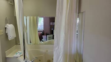 A bathroom with a bathtub, a sink, a mirror, and a shower curtain.