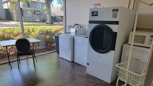 A laundry room with a washing machine, dryer, and a small table with a chair.