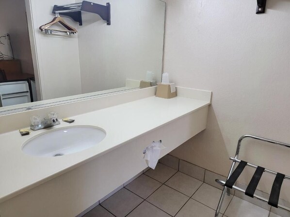 A bathroom with a white sink, a mirror, a towel rack, and a towel hanging on the wall.