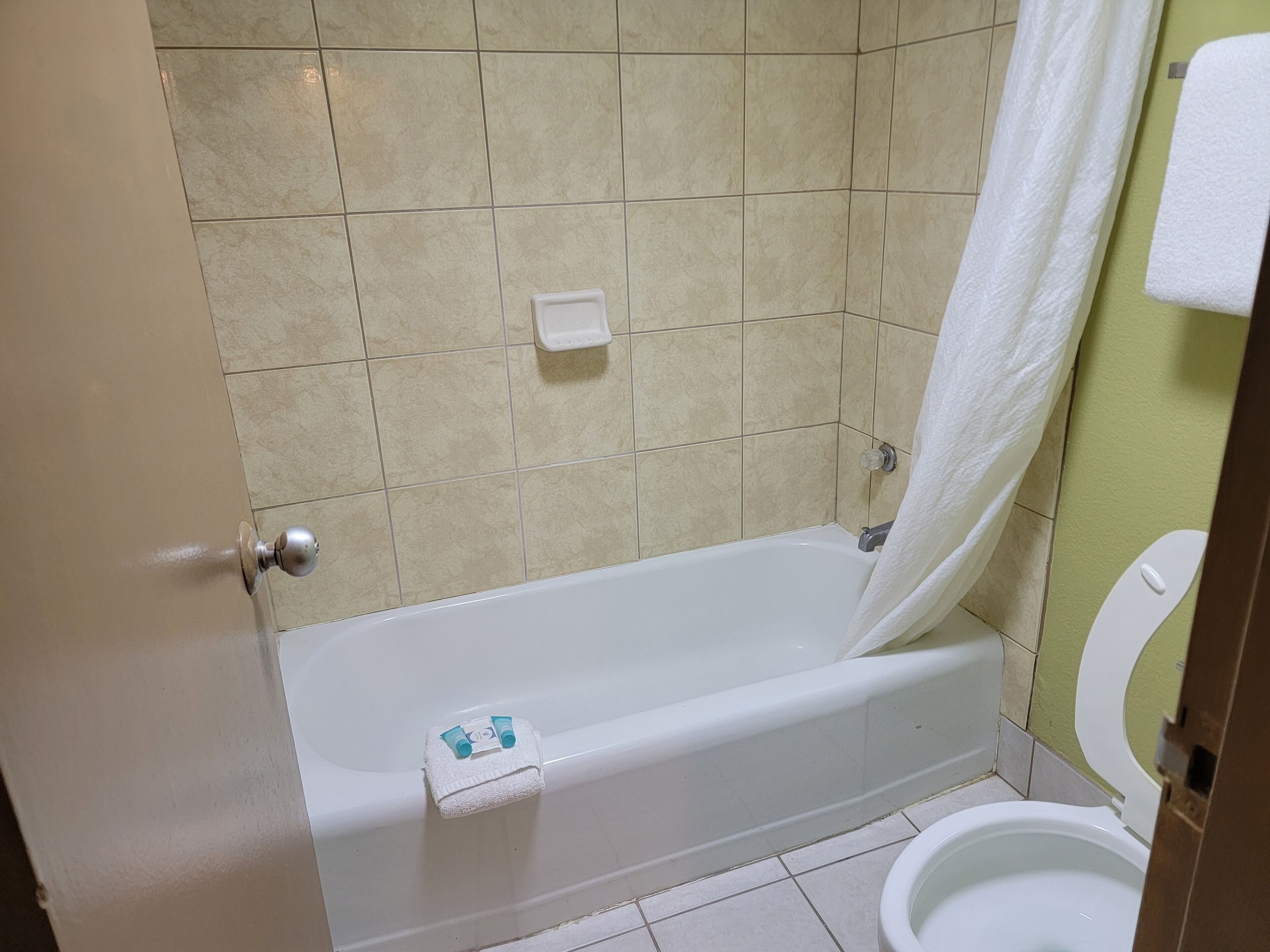 A bathroom with a bathtub, toilet, and a towel rack.