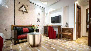 Una sala de estar con un sofá, una mesa de centro, un televisor y un suelo estampado.