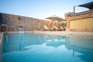 Una piscina al aire libre, sillones reclinables de piscina