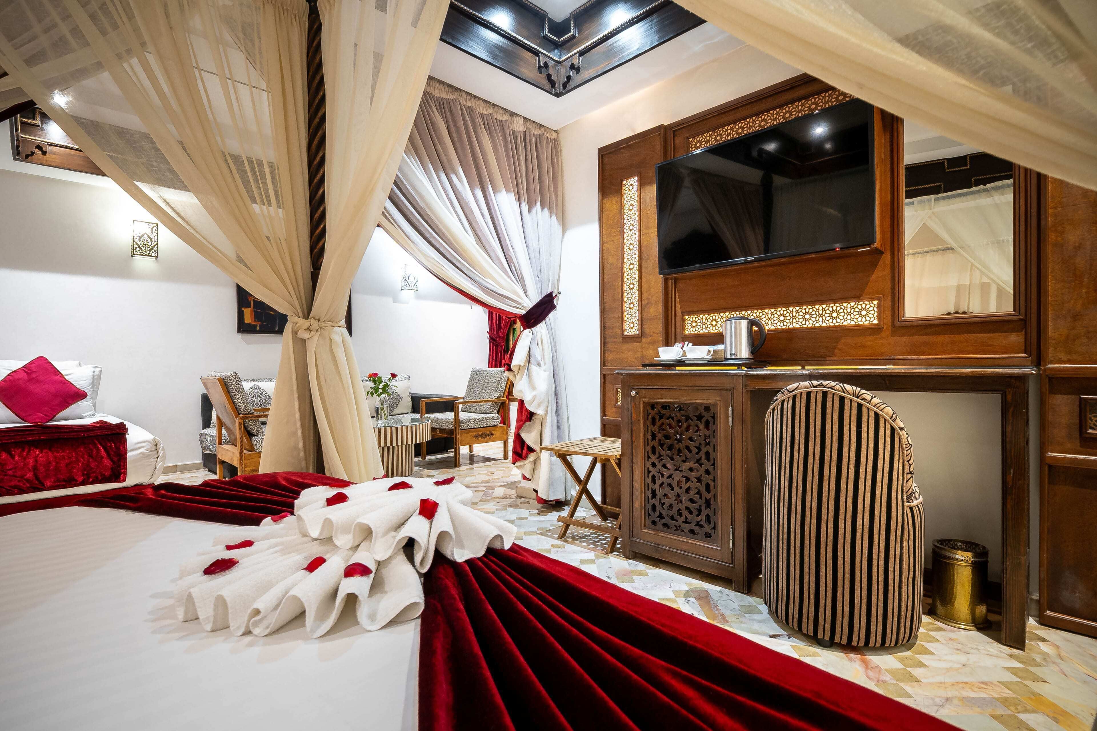 Ein Hotelzimmer mit Bett, Schreibtisch, Stuhl, Fernseher und einem dekorativen Spiegel.