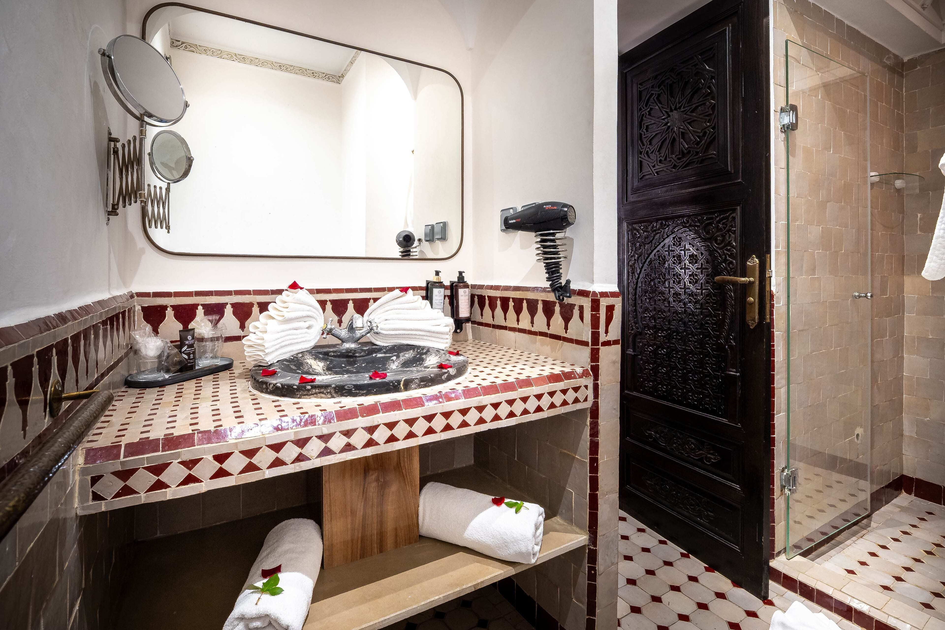 Een badkamer met een wastafel, spiegel, handdoekrek en douche.
