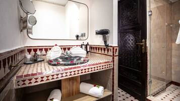 A bathroom with a sink, mirror, towel rack, and shower area.