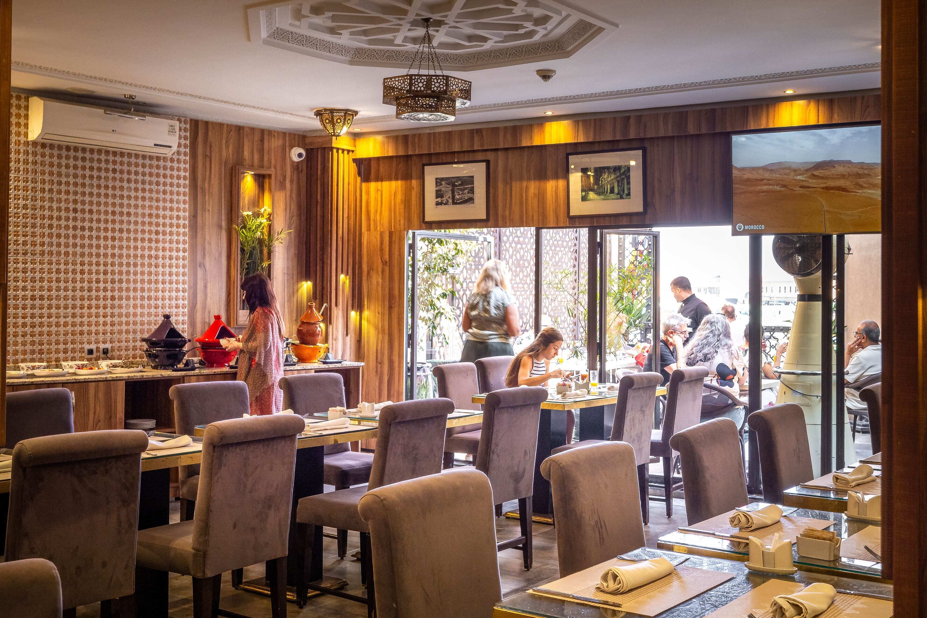A restaurant with indoor seating, a TV screen, and a view of the outdoor patio area.