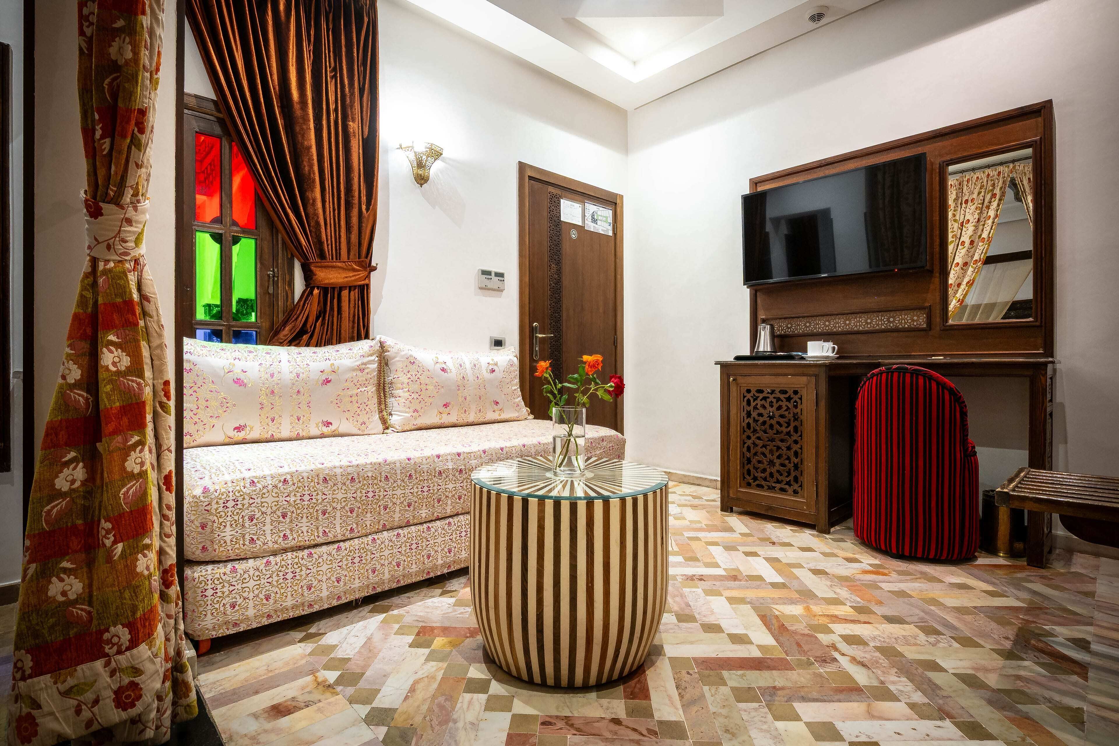 A living room with a sofa, a round table, a television, and a patterned floor.