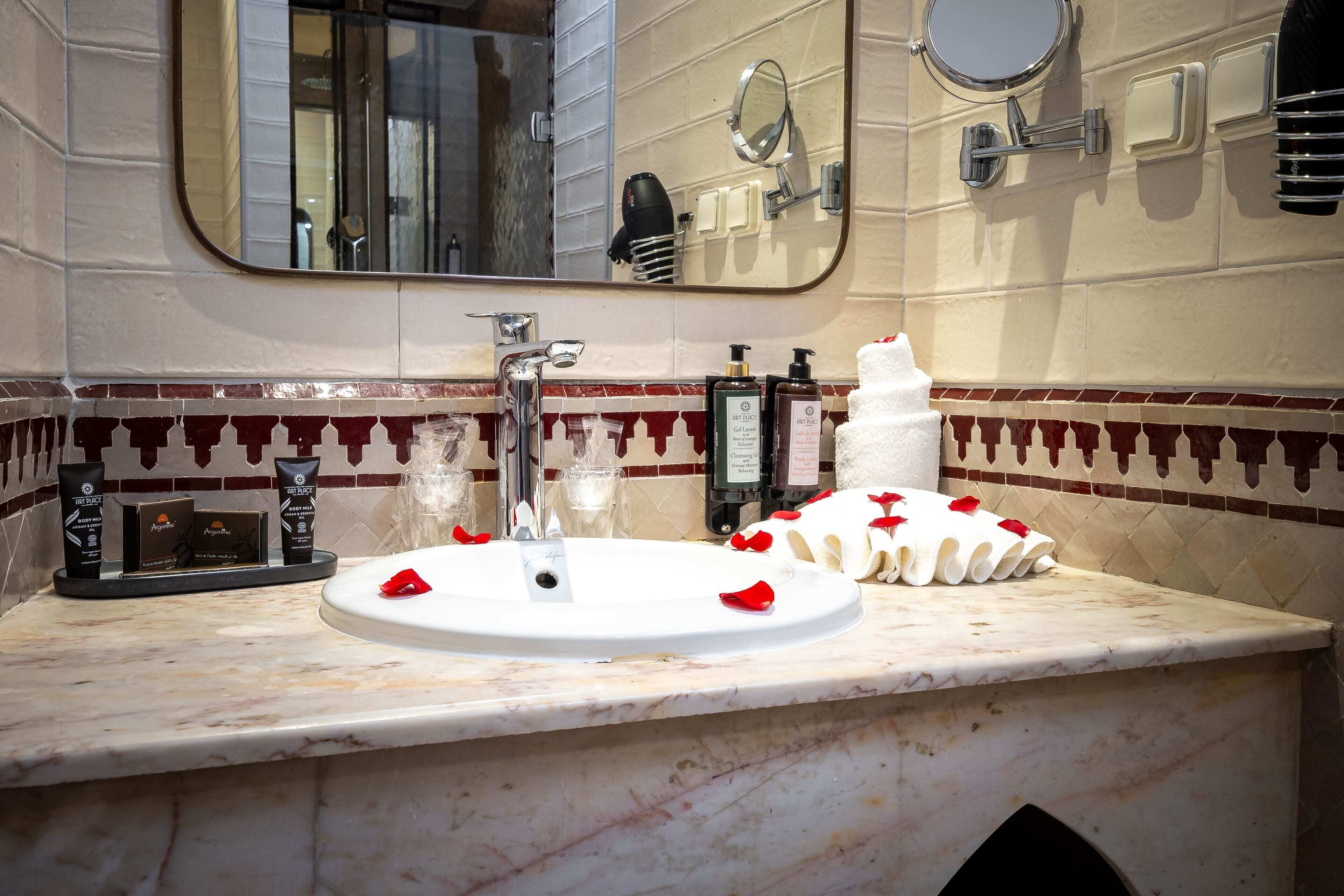 A bathroom with a sink, mirror, and toiletries.