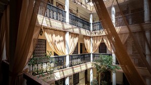 Un atrio de varios niveles con balcones, columnas y plantas colgantes.